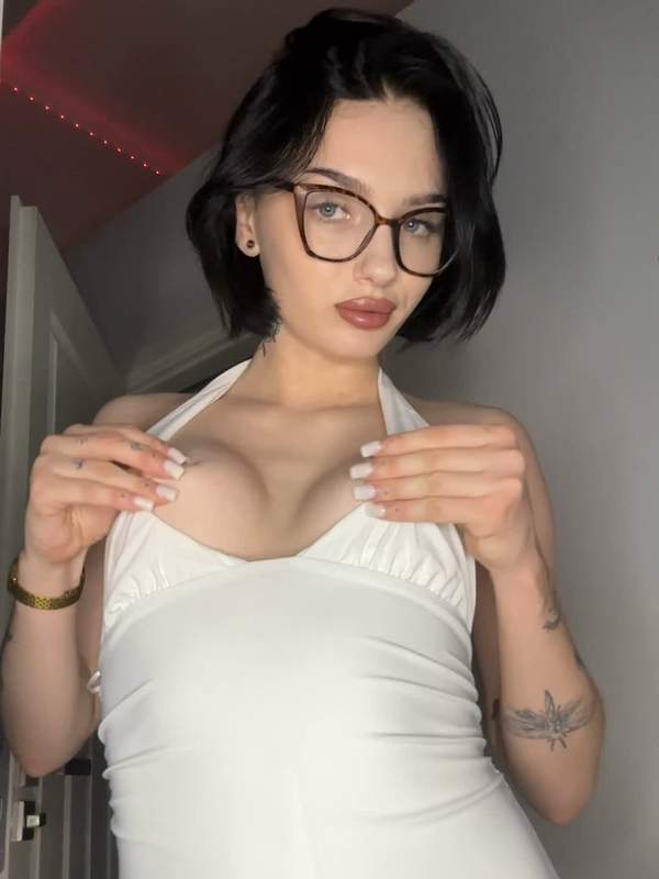 Junge Frau mit Brille und Tätowierung zeigt Solo-Onlyfans-Content