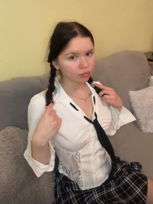 Brünette Teenagerin in Schuluniform mit Zöpfen und Minirock