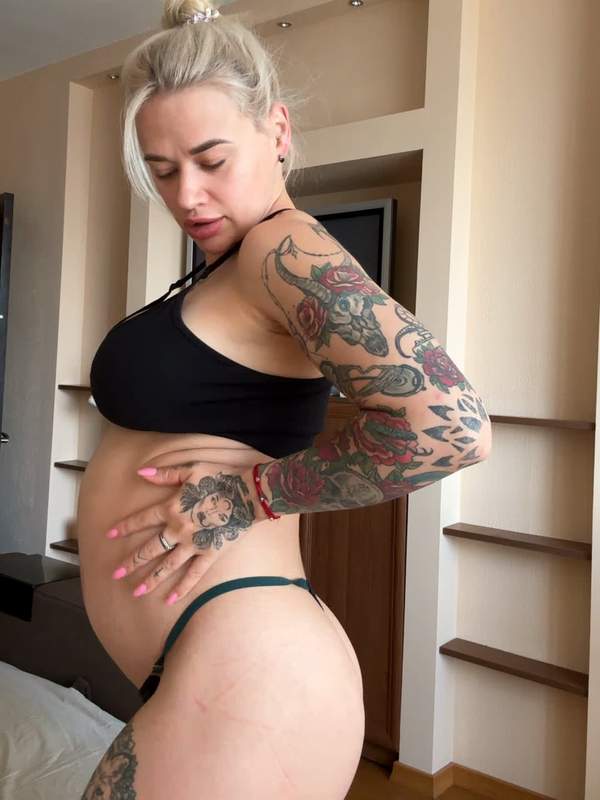 Schwangere Mutter mit Tätowierung und Bauchnabelpiercing