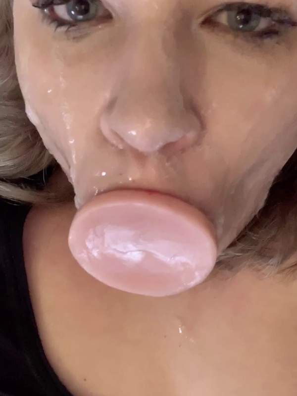 Sie lässt ein rosa Dildo in den Mund gleiten und sabbert.