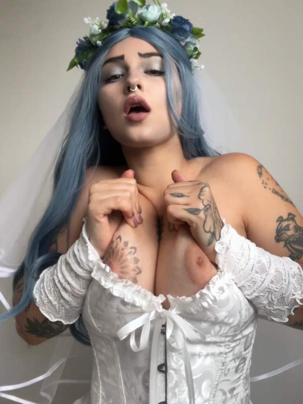 Braut mit blauen Haaren und Tätowierung zeigt nackte Brüste