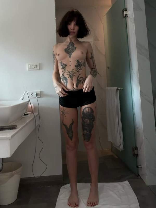 Brünette mit Tätowierung zeigt sich nackt und neigt sich zum Kuss
