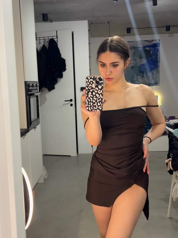 Süßes Mädchen macht Solo-Spiegel-Selfie in kleinem schwarzen Kleid