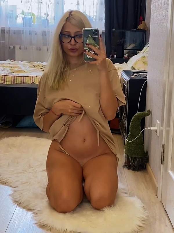 Blondes Mädchen mit Brille zeigt ihre nackten Brüste im Spiegel