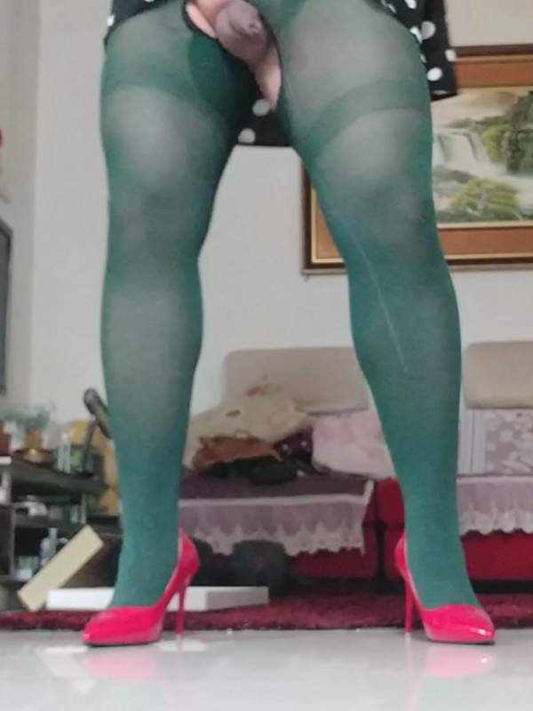 Transvestit in grünen Strümpfen und roten High Heels