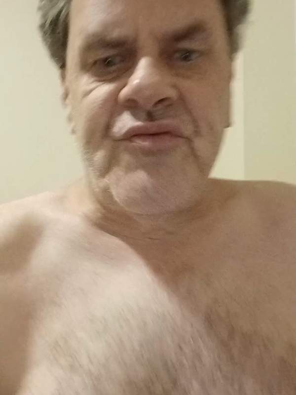 Reifer Mann mit behaartem Brustkorb wischst sich im Selfievideo