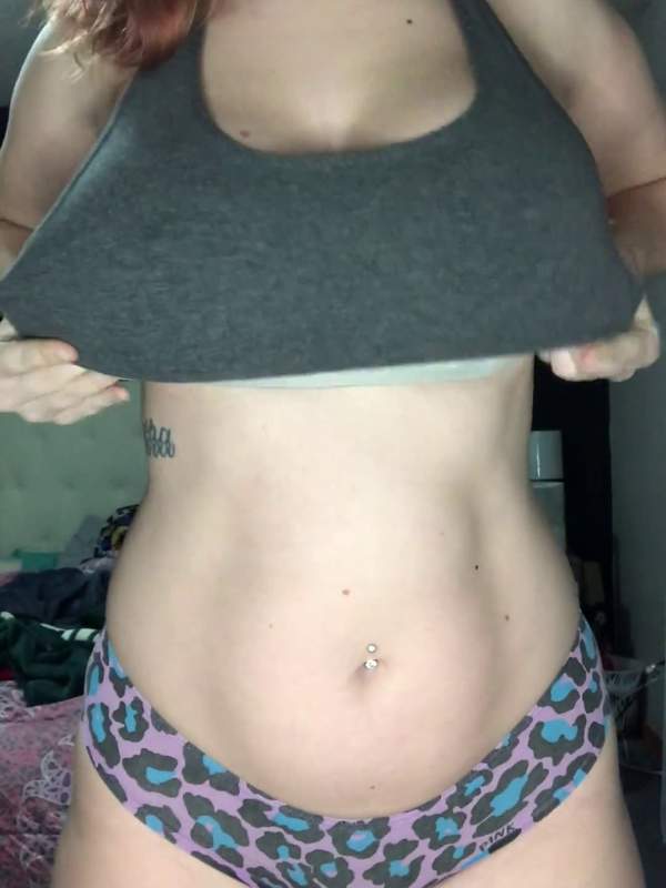 Naughty Vixen zeigt nackte Brüste unter grauem Tanktop