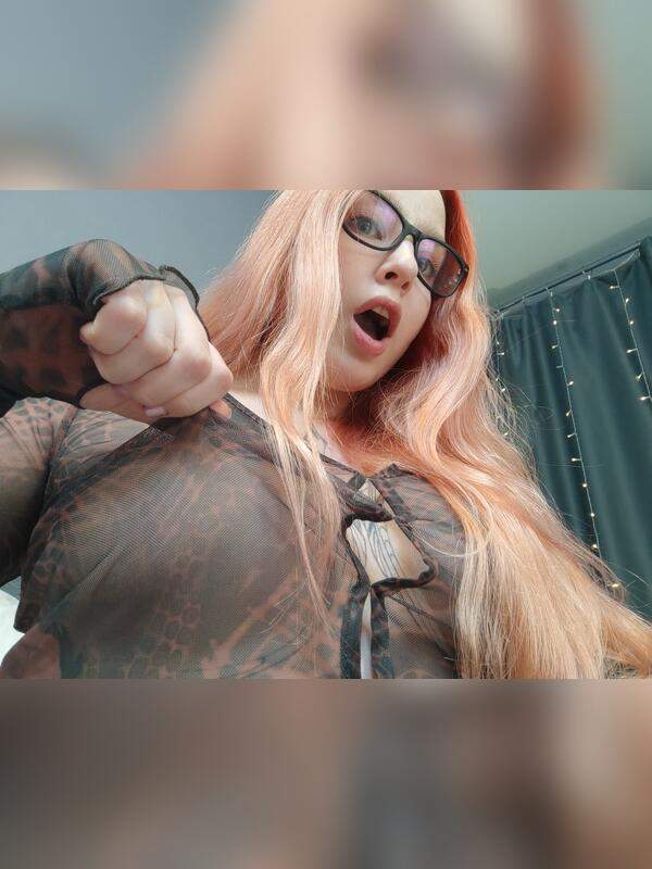 Mädchen mit Brille und Tätowierung zeigt ihre großen natürlichen Brüste