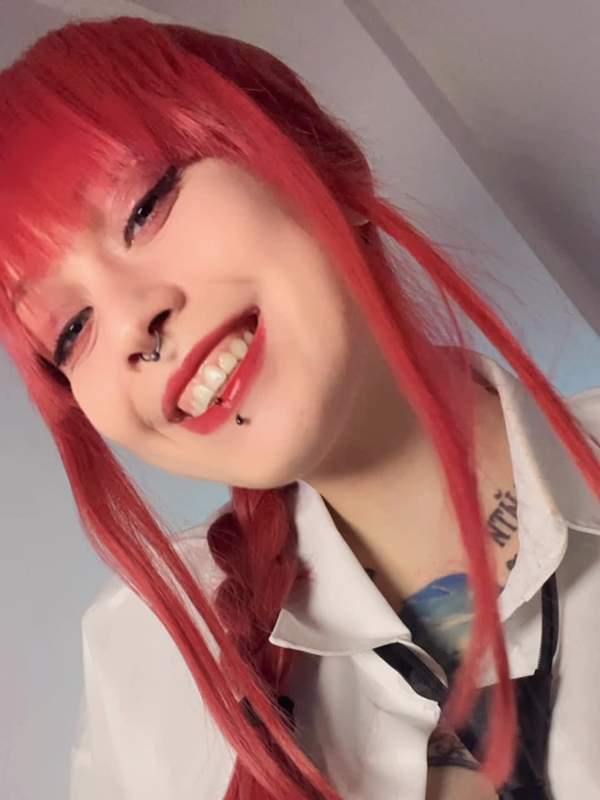 Sie zeigt Tätowierung und bunte Haare