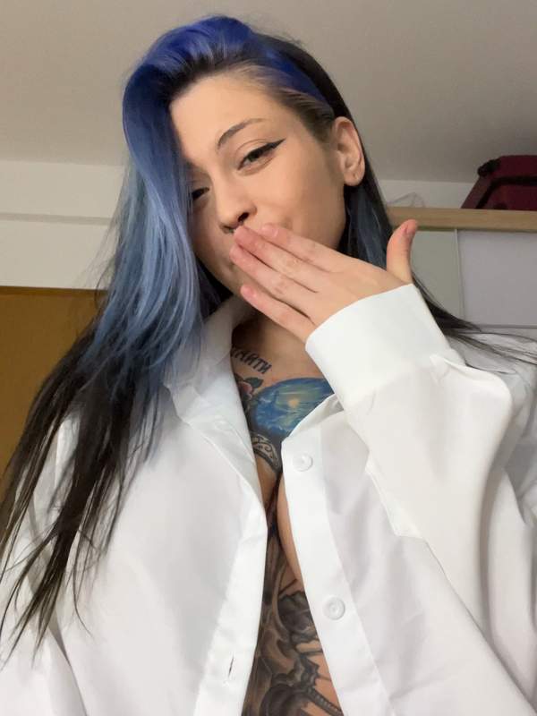 Brünette mit Tattoos und bunter Mähne neckt im Bett