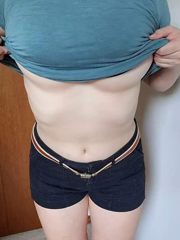 Junge Frau in blauem Oberteil zeigt ihre großen Brüste öffentlich und lässt sie hüpfen.