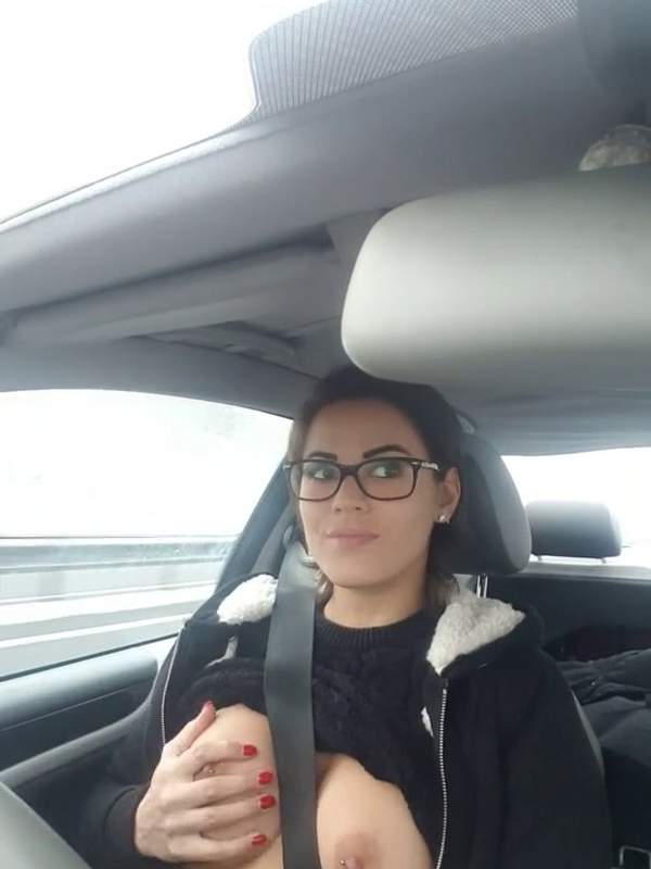 Frau mit Nippelpiercing zeigt sich im Auto