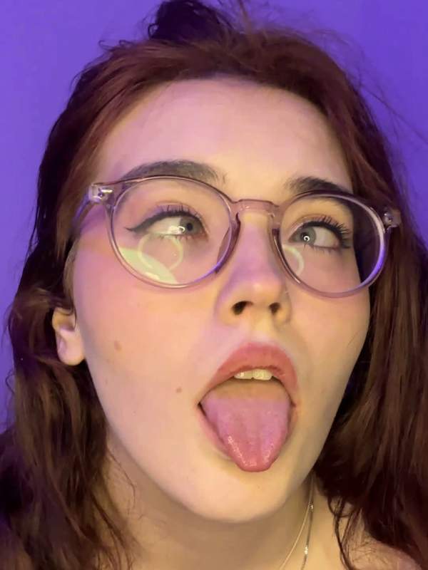 Brünette mit Brille zeigt Zunge und rollt die Augen