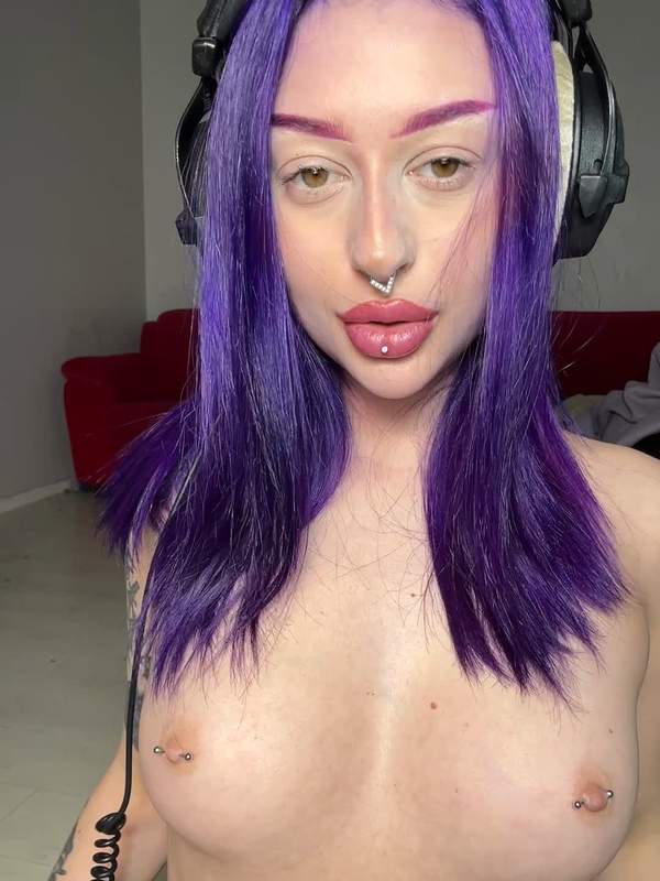 Nette Frau mit lila Haaren und Piercings zeigt ihre großen Brüste