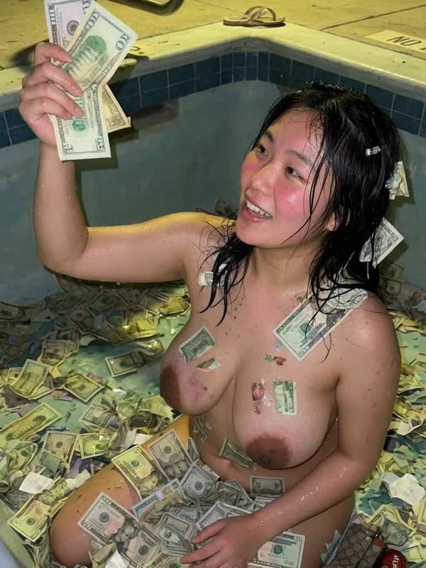 Brünette Asiatische Frau entspannt sich nackt im Bad mit Geld