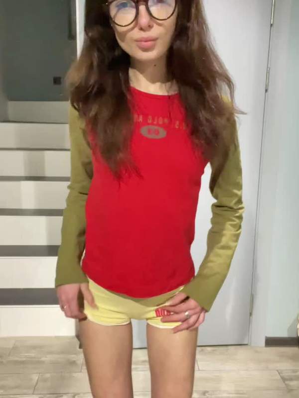 Junges Mädchen mit Brille und Bauchnabelpiercing hebt Shirt