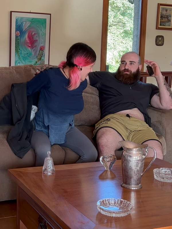 Tätowierte Frau reitet ihren Mann rückwärts auf dem Sofa