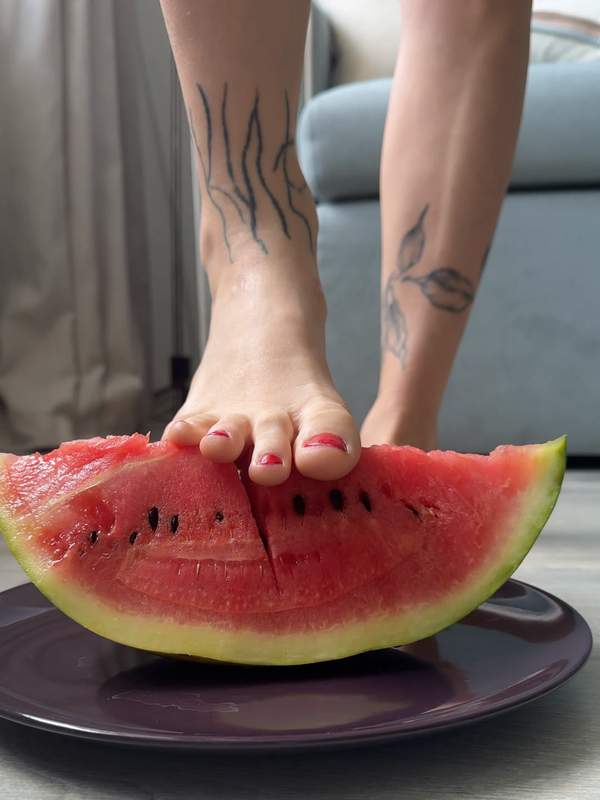 Junge Frau mit Melone und Tätowierung zeigt Fußfetisch