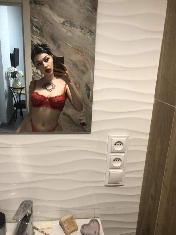 Junges Mädchen mit Tätowierung zeigt hübsche rote Unterwäsche im Badezimmer