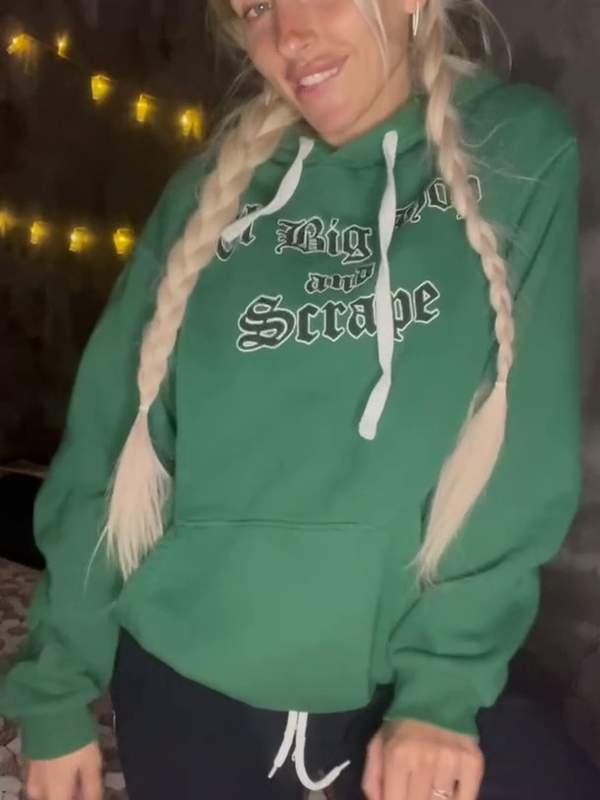 Blonde Amateur mit Zöpfen und grüner Kapuzenjacke auf dem Bett