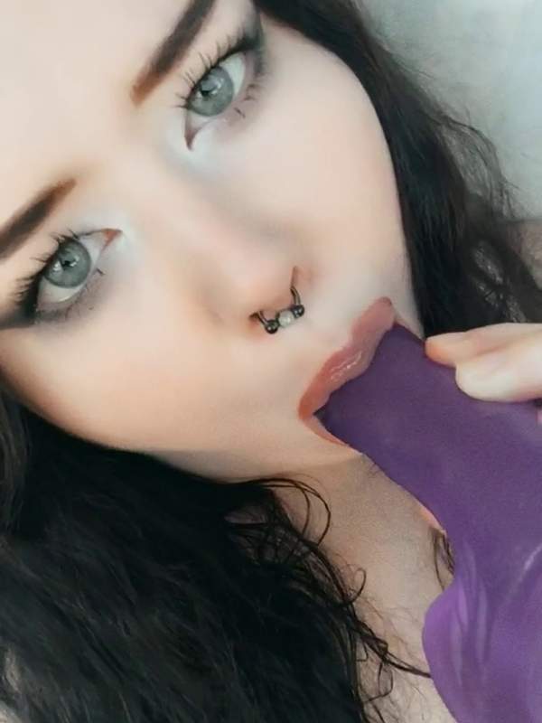 Junge Frau saugt lüstern auf lila Dildo