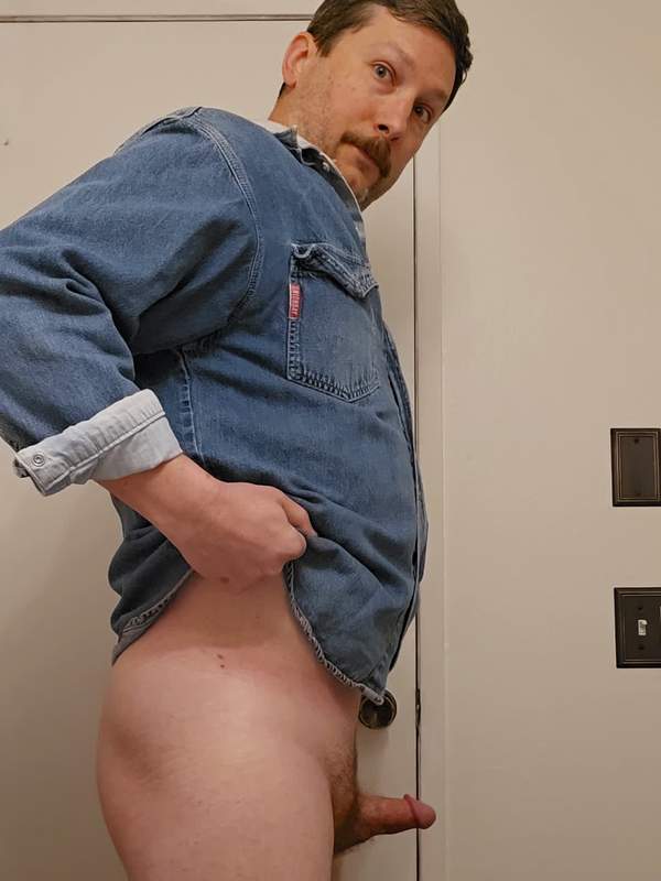 Mann mit Schnurrbart in Jeanshemd hat kleinen Schwanz