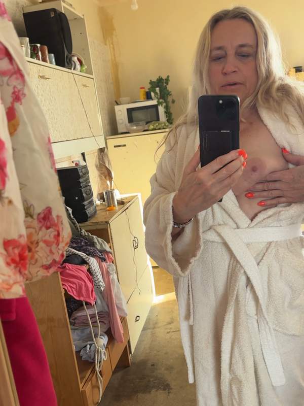 Blonde Mutter steht im Spiegel und zeigt ihre hängenden Titten durch das durchsickernde Badetuch.