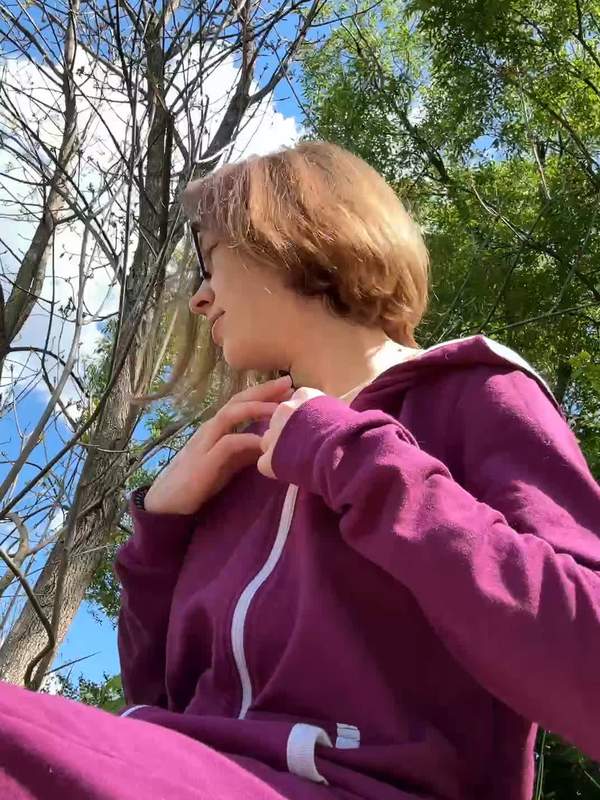 Nackte Frau in Brille und magentafarbenem Hoodie zeigt sich draußen