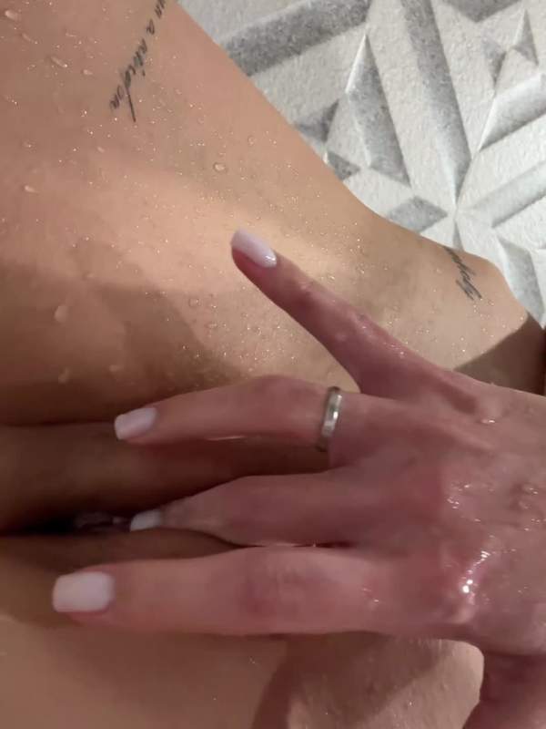 Junge Frau rasiert sich die Brust in der Dusche