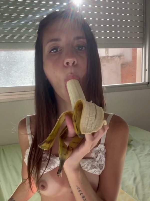 Brünette mit Bauchnabelpiercing lutscht Banane