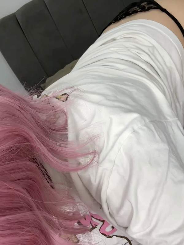 Rosahaarige Femboy in rosa Höschen kniet und schaut zurück