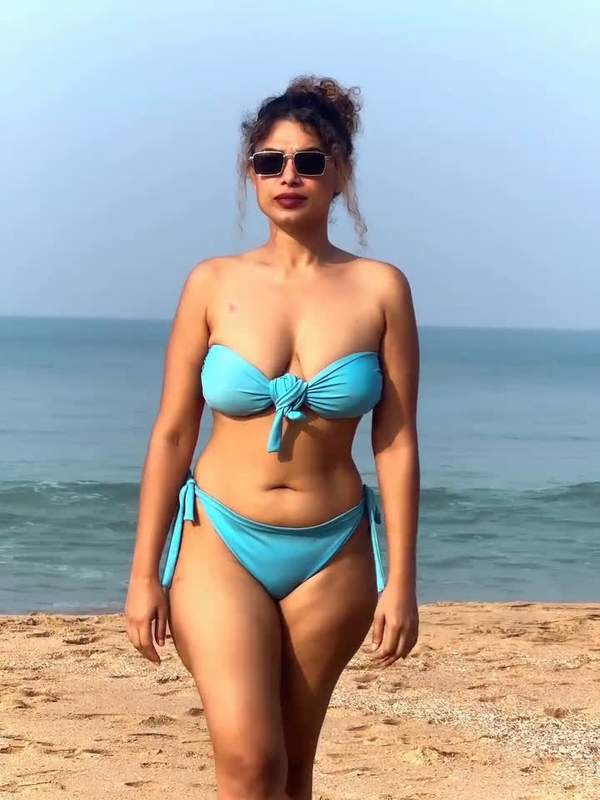 Schönes Mädchen posiert im blauen Bikini am Strand